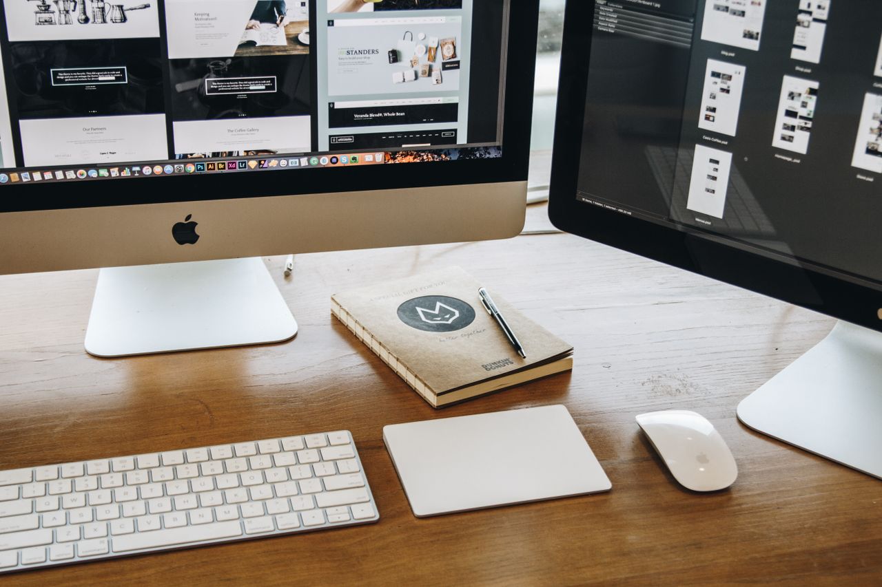 Un espace de travail épuré avec deux écrans, un clavier, une souris et un carnet, pensé pour favoriser la productivité.