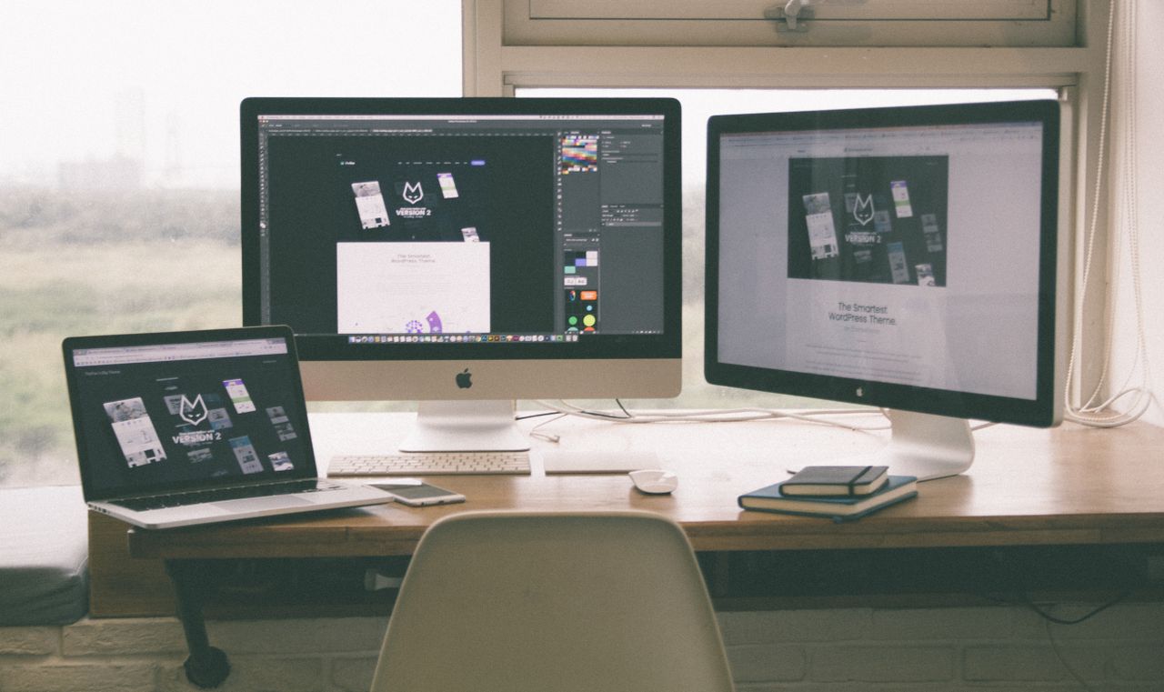 Espace de travail élégant et performant avec plusieurs écrans, un ordinateur portable et un smartphone, mettant en avant un projet de web design.